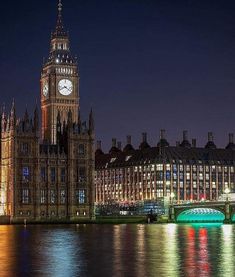 the big ben clock tower towering over the city of london at night with lights reflecting in the water