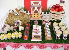 a table filled with lots of food on top of a grass covered field next to a red barn