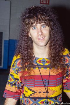 a man with long curly hair wearing a colorful shirt