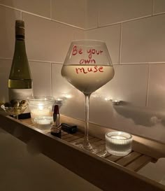 a wine glass sitting on top of a wooden shelf next to a bottle and glasses