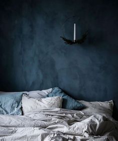 an unmade bed with white sheets and blue walls