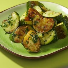 a green plate topped with zucchini and other vegetables