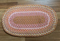 an orange and white round rug on a wooden floor with wood floors in the background