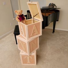 a teddy bear sitting in a wooden box on top of blocks that spell out letters