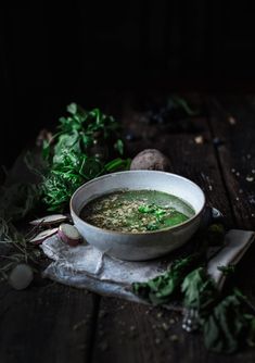 a white bowl filled with soup sitting on top of a table next to some vegetables