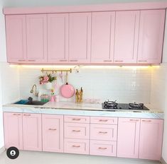 a kitchen with pink cabinets and white counter tops