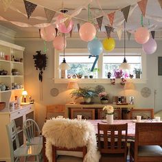 a dining room filled with lots of furniture and balloons hanging from the ceiling above it