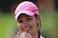 a woman wearing a pink hat and holding a toothbrush in her mouth while smiling at the camera