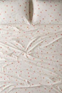 an unmade bed with white sheets and orange polka dots on the comforter is shown