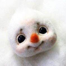 a close up of a stuffed animal on a white surface with black eyes and an orange nose