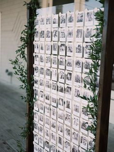 a wall with pictures and greenery hanging on it's sides in front of a building