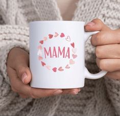 a woman holding a white coffee mug with the word mam printed on it and hearts