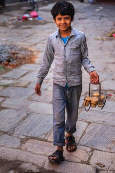 a young boy is walking down the street holding a lantern in one hand and smiling at the camera