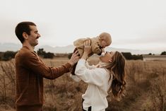 a man holding a baby up to his face as he holds it in the air