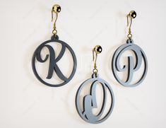 two pairs of earrings with the letter k on them