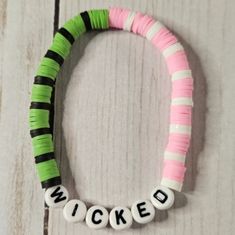 a close up of a bracelet on a wooden surface with words written in white and green