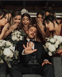 a group of bridesmaids and groomsmid posing for a photo with their hands in the air