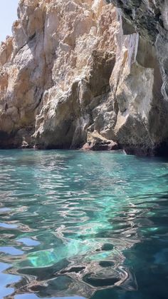 the water is crystal blue and there are some rocks in the backgrouds