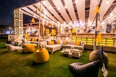 an outdoor seating area with yellow and white striped awnings on the grass at night