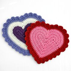 two crocheted heart coasters sitting next to each other on a white surface