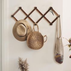 two hats hanging on a wall next to a vase with flowers and other items in it