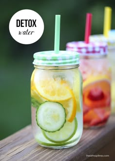 two mason jars filled with cucumber, lemon and limeade on top of a wooden table