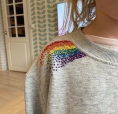 a woman wearing a sweater with a rainbow painted on it