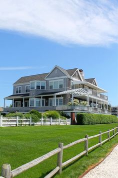 a large house sitting on top of a lush green field next to a wooden fence