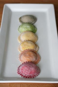 a row of different colored pastries on a white plate with wood table in the background