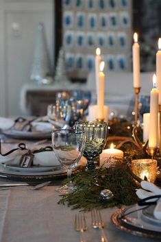 the table is set with candles, dishes and silverware for an elegant christmas dinner