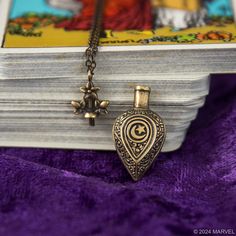 a necklace with an ornate design on it and a star hanging from the front, sitting next to a book