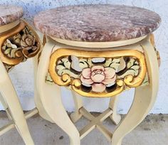 two stools sitting next to each other on top of cement ground with flowers painted on them