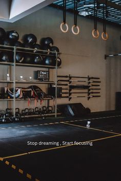 an empty gym with kettles and exercise equipment hanging on the wall, along with overhead lighting