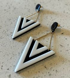 This is a fun pair of black and white acrylic drop earrings from the 1990's. The earrings start with a black flat small round round dot top. The earrings then have 2 gold bars hanging below, which are connected to a large black and white triangle acrylic triangle. The earrings are in new old stock condition. The earrings measure 3 1/2" long and 1 1/4" wide. A fantastic gift for yourself or someone you love! Diy Soda, Round Round, Black And White Earrings, Gold Bars, White Earrings, Gold Bar, White Acrylic, Acrylic Earrings, Earrings Dangle