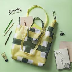 a yellow and green tote bag sitting on top of a table next to eyeglasses