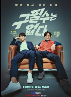 two men sitting on top of a couch in front of a poster for the movie