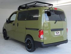 a green van parked in a garage with a basket on the back of it's roof