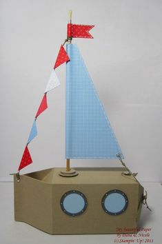 a cardboard boat with red, white and blue flags on it's sails is shown