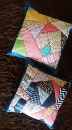 two decorative pillows sitting on top of a brown carpet next to each other and one has a colorful patchwork design