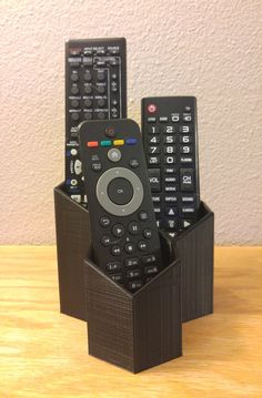 three remote controls in a black holder on a table