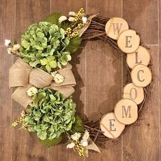 a welcome wreath with greenery and wood slices on the front, sitting on a wooden floor