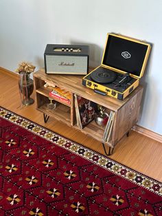 a record player sitting on top of a wooden cabinet next to a rug and vase