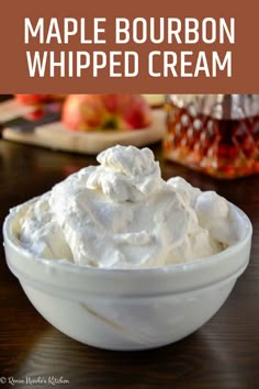 a white bowl filled with whipped cream on top of a wooden table next to a jar of maple bourbon whipped cream