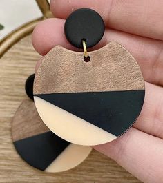 a person is holding a wooden and black disc shaped earring in their left hand