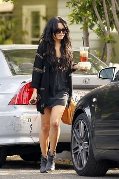 a woman walking down the street with a drink in her hand