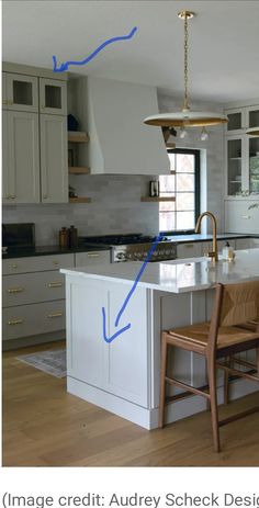 a kitchen with white cabinets and blue arrows pointing to the center island in the middle