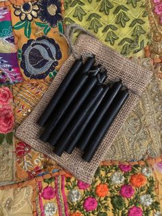 six black candles are sitting on a colorful cloth