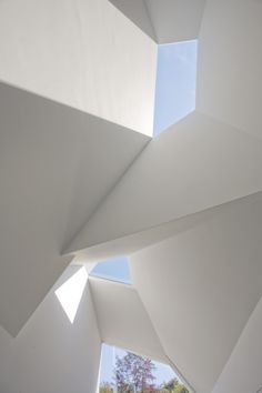 the interior of a modern building with white walls and roofing, looking up at the sky