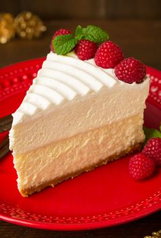 a piece of cheesecake on a red plate with raspberries