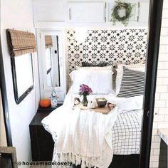 a bed with white sheets and black and white decor on the headboard in a small room